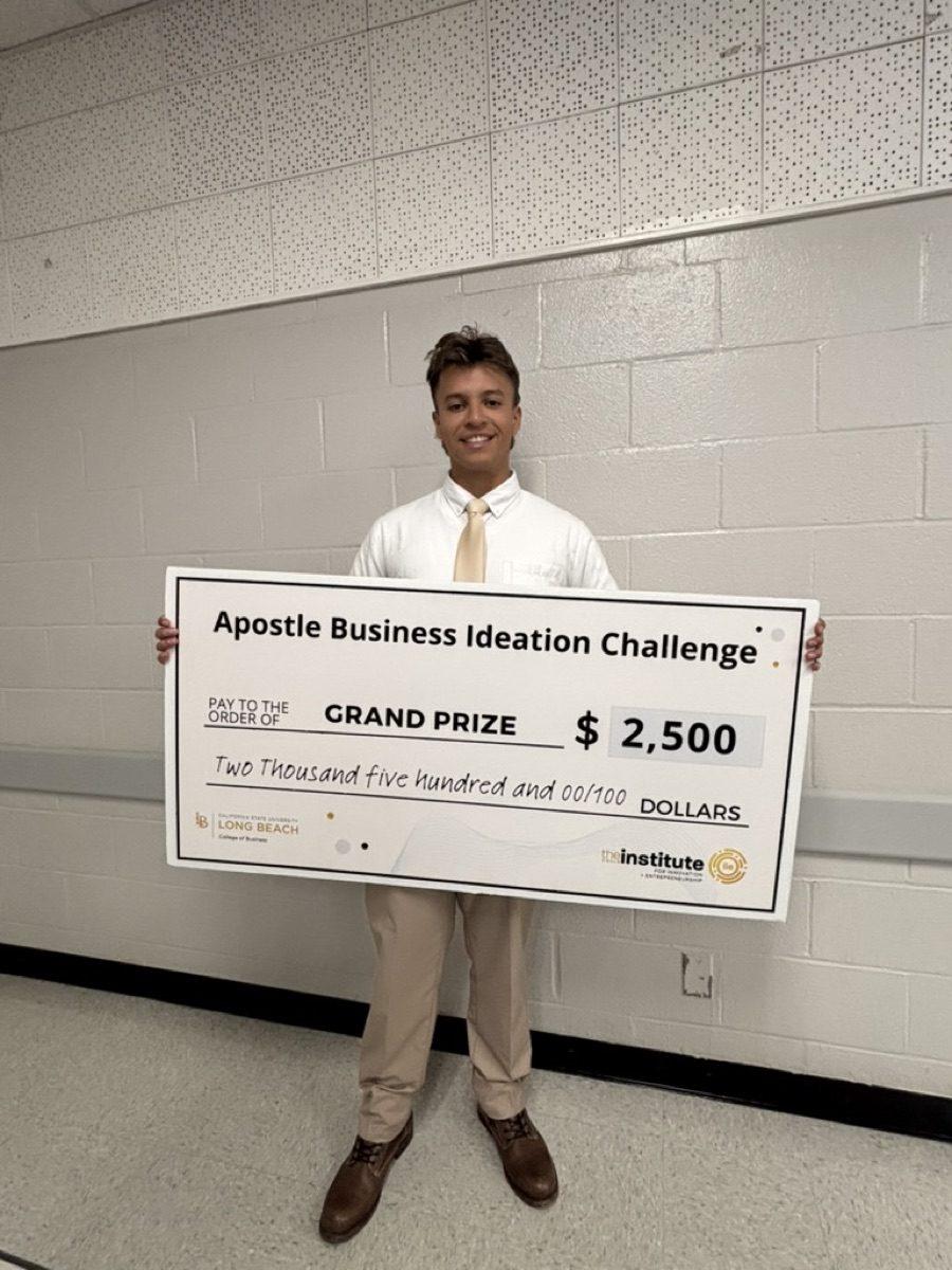 Christopher Carrillo holding the $2,500 grand-prize check from the Apostle Business Ideation Challenge