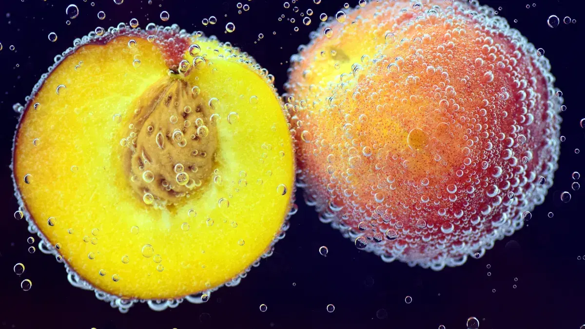Close-up of ripe peaches submerged in water with air bubbles, highlighting freshness and vibrant color.
