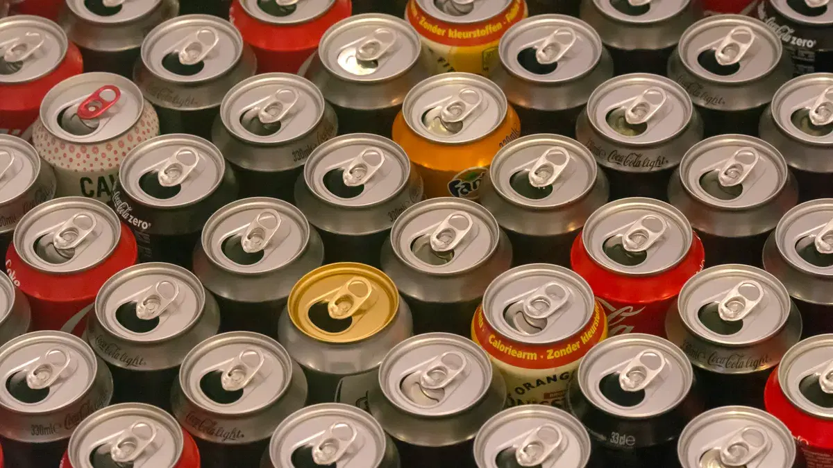 Top view of various aluminum soda cans lined up in colorful rows, highlighting recycle potential.