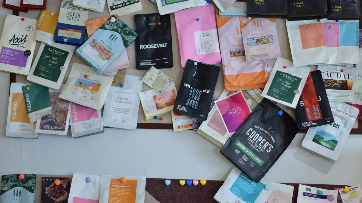 A diverse collection of coffee packages pinned to a bulletin board, showcasing various brands and designs.